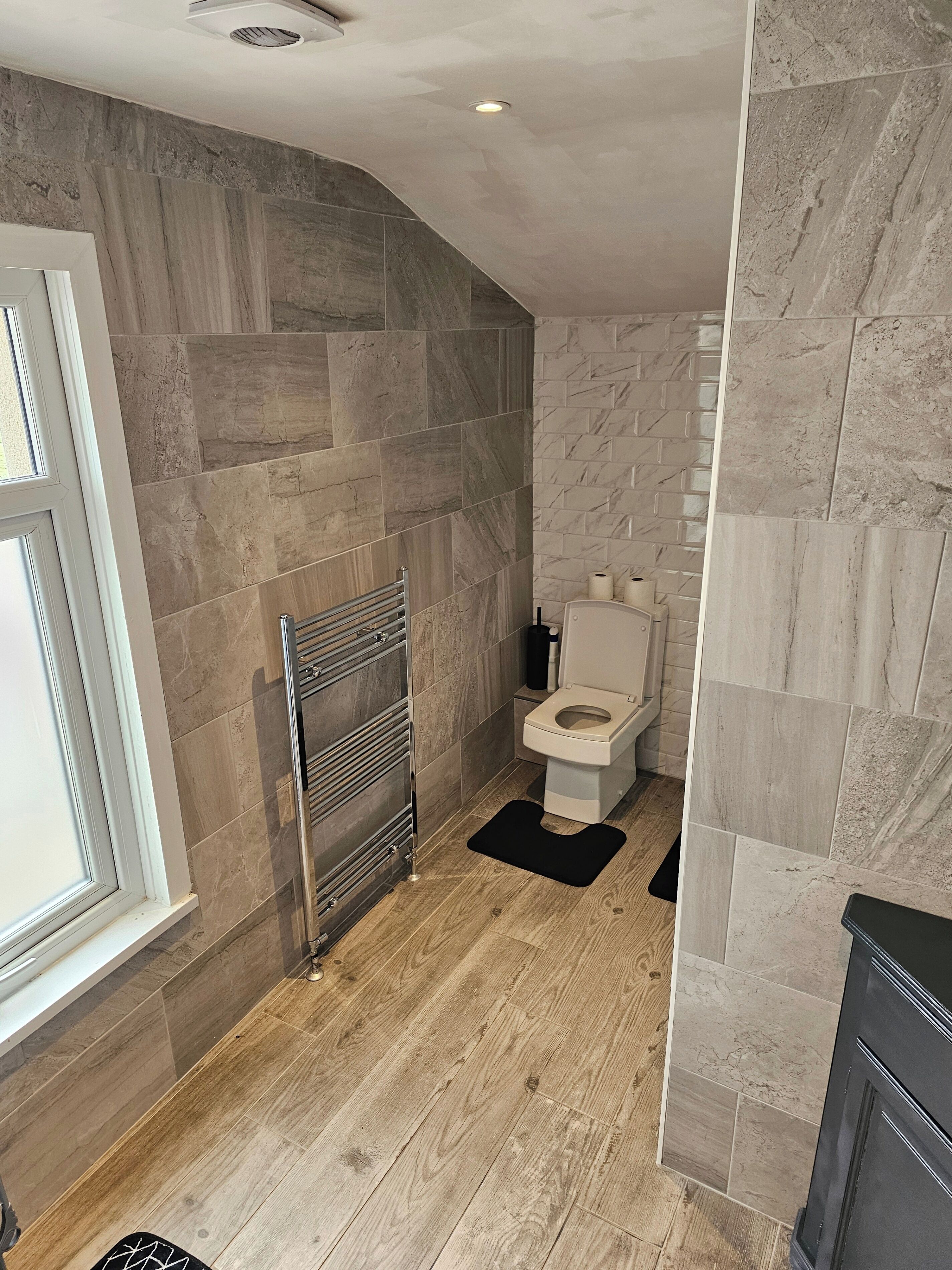 A modern bathroom with a shower, toilet, and a towel rack.
