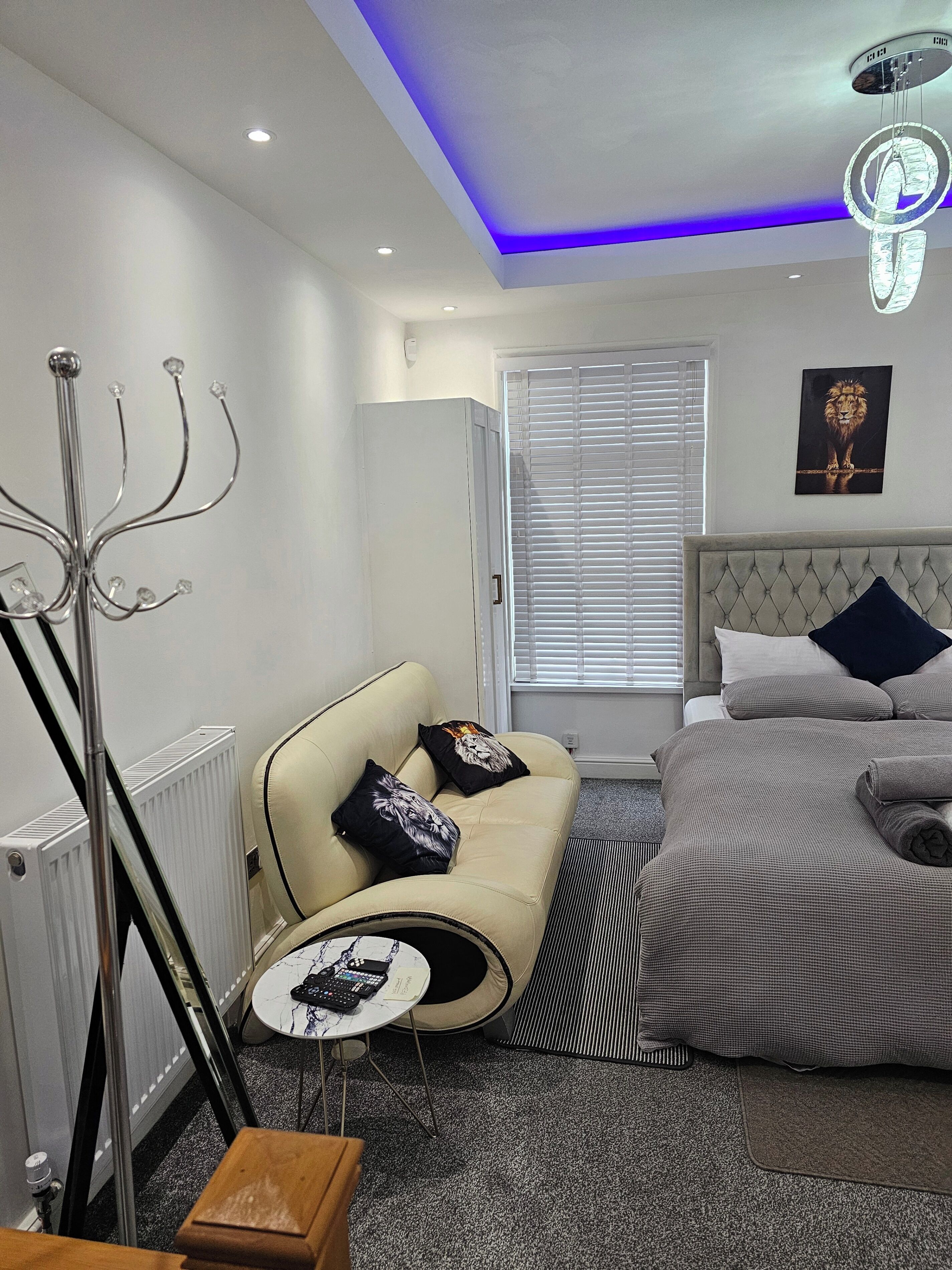 A modern bedroom with a bed, a sofa, a radiator, and a floor lamp.