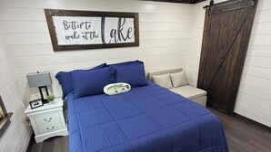 Un dormitorio con cama, mesita de noche, cómoda, ventilador de techo y un cartel en la pared.