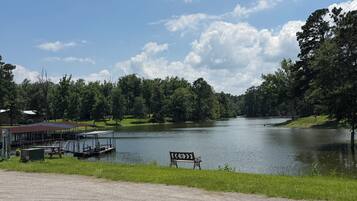 A lakeside view with a dock, a bench, and a building with a red roof.