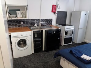 Eine kleine Küchenzeile mit Waschmaschine, Geschirrspüler, Herd und Kühlschrank.