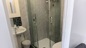 A bathroom with a glass-enclosed shower, a sink, and a toilet. - Studio Sleeps 2 With Parking (Oldbury)