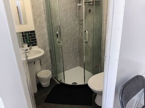 Et badeværelse med bruseniche, vask og toilet.