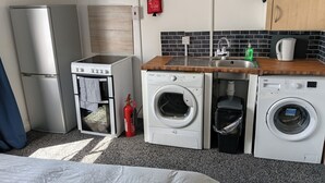 A compact kitchenette with a refrigerator, oven, microwave, and washing machine. - Studio Sleeps 2 With Parking (Oldbury)