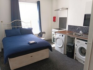 Ein Schlafzimmer mit Bett, Waschmaschine, Spüle und Herd.