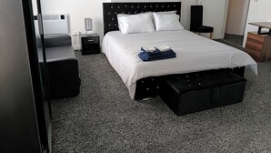Ett hotellrum med en säng, ett nattduksbord, ett skrivbord, en garderob och en liten sittgrupp.