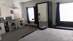 Ett hotellrum med en säng, en tvättmaskin, en spegel och en stol.