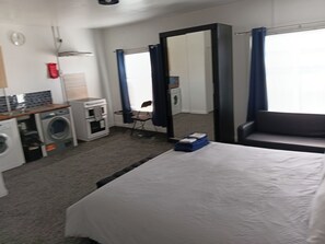 A hotel room with a bed, a washing machine, a mirror, and a chair. - Cozy Studio in Oldbury With Extra Beds (Oldbury)