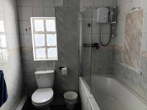 Ein Badezimmer mit Toilette, Bidet, Badewanne und einem Fenster.