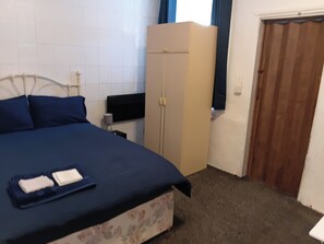 Ein Schlafzimmer mit Bett, Kleiderschrank, Schreibtisch und Tür.