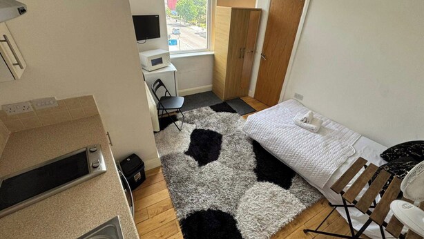 A compact hotel room with a bed, a desk with a computer, a chair, and a view of the street through a window. - Upper Holloway Studio, 1 Min to Station, Sleeps 2 (London)