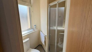 A bathroom with a toilet, a window, a towel rack, and a glass shower enclosure. - Upper Holloway Studio, 1 Min to Station, Sleeps 2 (London)