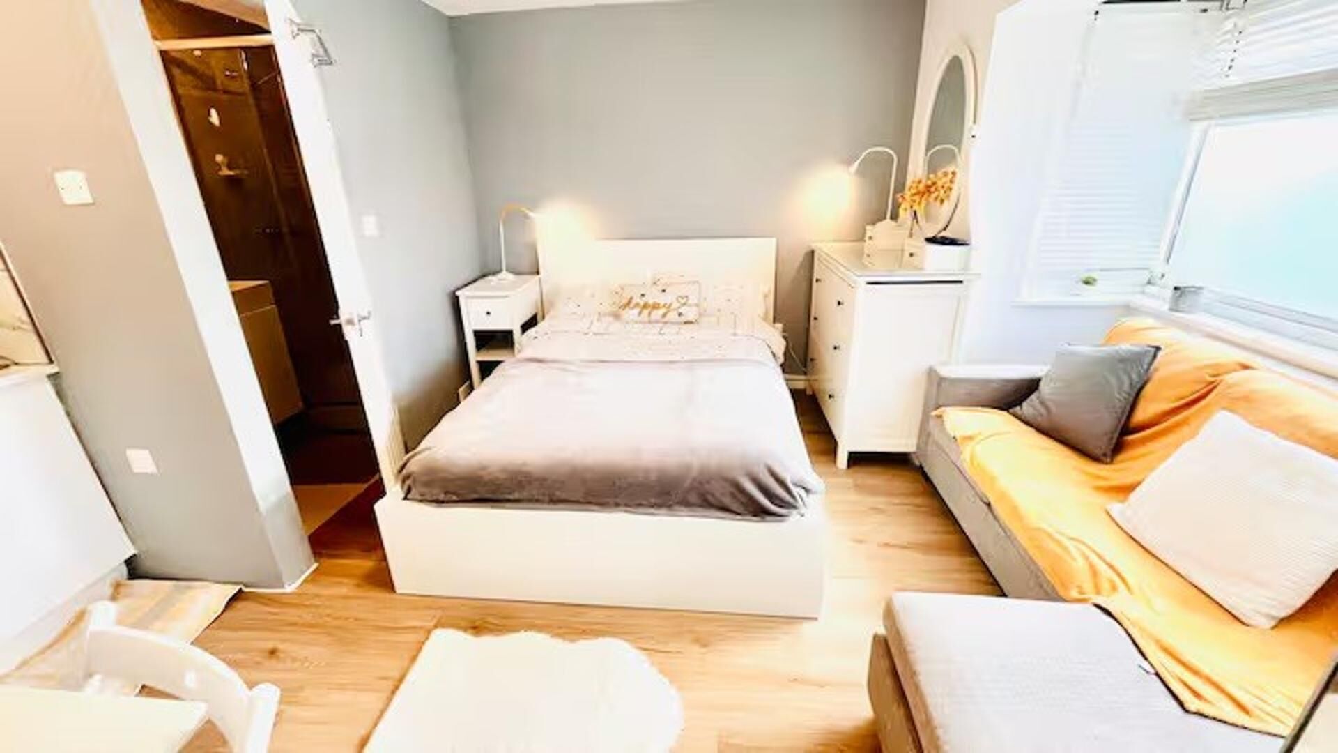 A bedroom with a bed, bedside table, dresser, and a window.