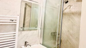 A modern bathroom with a glass-enclosed shower, a white sink, and a mirror. - Studio Sleeps 2 With Shared Hot Tub (London)
