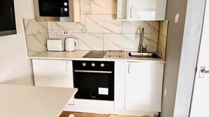 A compact kitchen with a microwave, toaster, sink, and oven. - Studio Sleeps 2 With Shared Hot Tub (London)