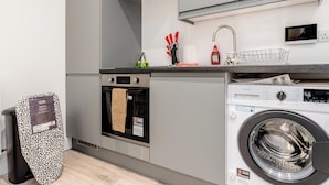Eine moderne Küche mit Einbauofen, Waschmaschine und Mülleimer.