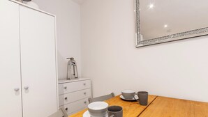 A wooden dining table with a white cabinet and a mirror on the wall.