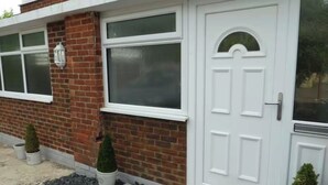 A house with a white front door, a brick facade, and two small potted plants. - Studio Sleeps 2 - Pets Welcome - Enclosed Garden (Bognor Regis)