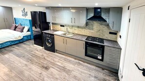 Une cuisine de taille réduite équipée d’un lave-linge, d’une cuisinière et d’un évier.