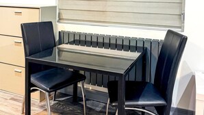 Un petit coin repas avec une table et deux chaises, un radiateur et un meuble.