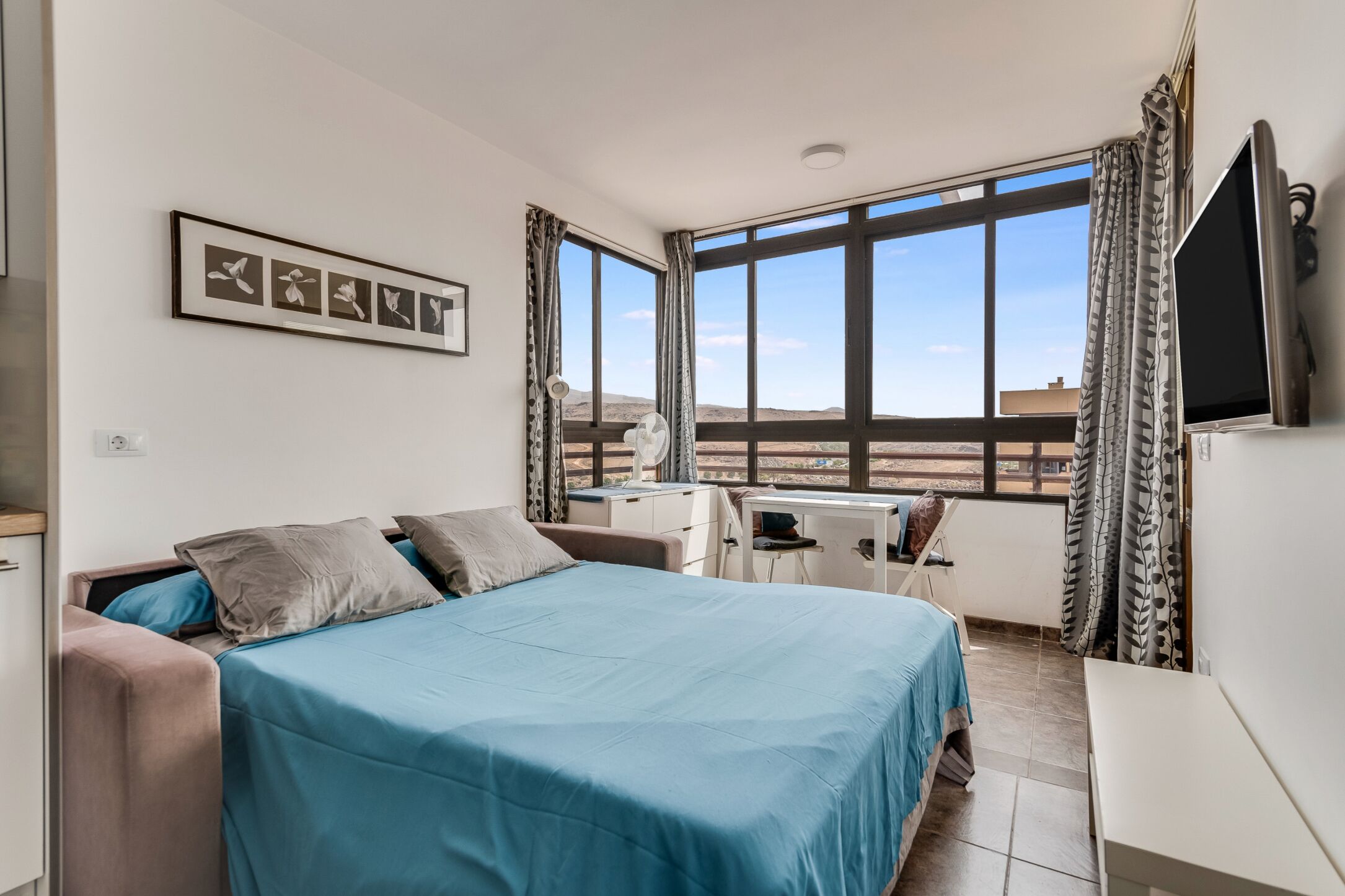Habitación de hotel con cama, escritorio, silla y televisor.