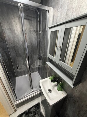 Ein modernes Badezimmer mit einer Duschkabine aus Glas, einem weißen Waschbecken und einem Spiegelschrank.