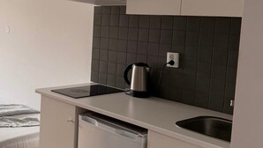 Una kitchenette compacta con lavavajillas integrado, tetera y pileta.