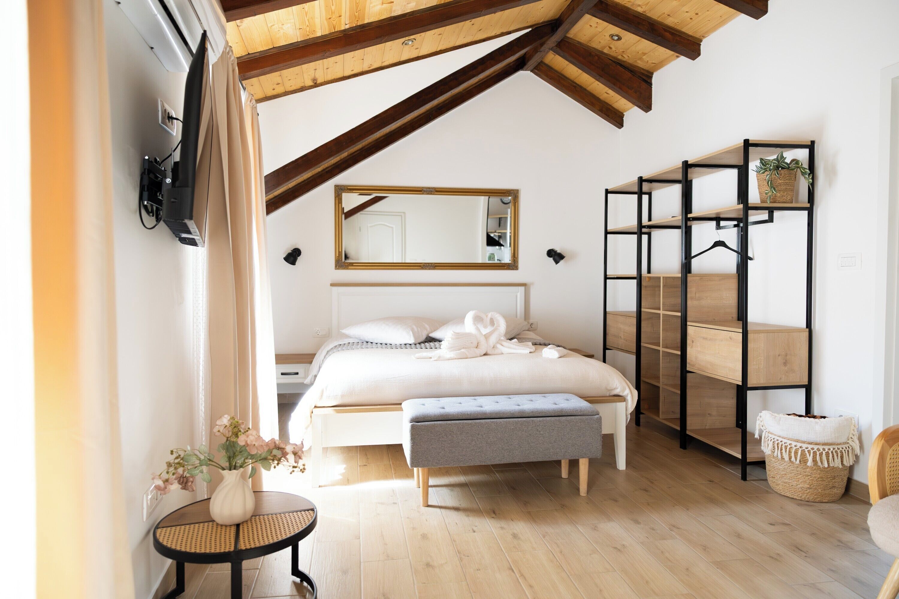 Une chambre à coucher comprenant un lit, une table de chevet, un banc et une étagère.