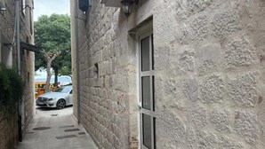 A narrow alleyway with stone walls, a door with a window, and a doormat. - Beautiful Studio Apartment Close to the Beach (Kastela)