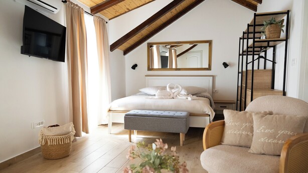 A bedroom with a bed, a chair, a bedside table, a mirror, a TV, and a staircase. - Beautiful Studio Apartment Close to the Beach (Kastela)