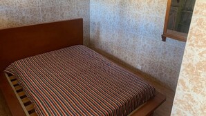 A small, single-bed room with a wooden headboard, a patterned bedspread, and a textured wall. - Sleeps2-freeparking-walktobeach-carvoeiro (Lagoa)