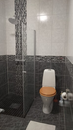 A bathroom with a shower, toilet, and a tiled floor. - Studio Sleeps 1 in Sundbyberg (Sundbyberg)
