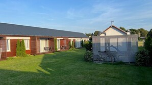 A residential property with a two-story house, a covered patio, and a fenced yard with a bicycle. - Single-story Holiday Homes in a Quiet Area (Kamien Pomorski)