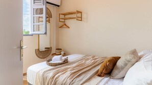 A bedroom with a bed, a hanging wooden shelf, a basket, and a towel rack. - Apartement Bèt a Fé, Les Trois-Ilets (Les Trois-Îlets)