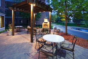 Un patio al aire libre con chimenea de piedra, asientos y una pérgola.
