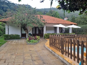 A villa with a tiled roof, a stone-paved entrance, and a wooden fence. - Casa Lírio  (Teresópolis)