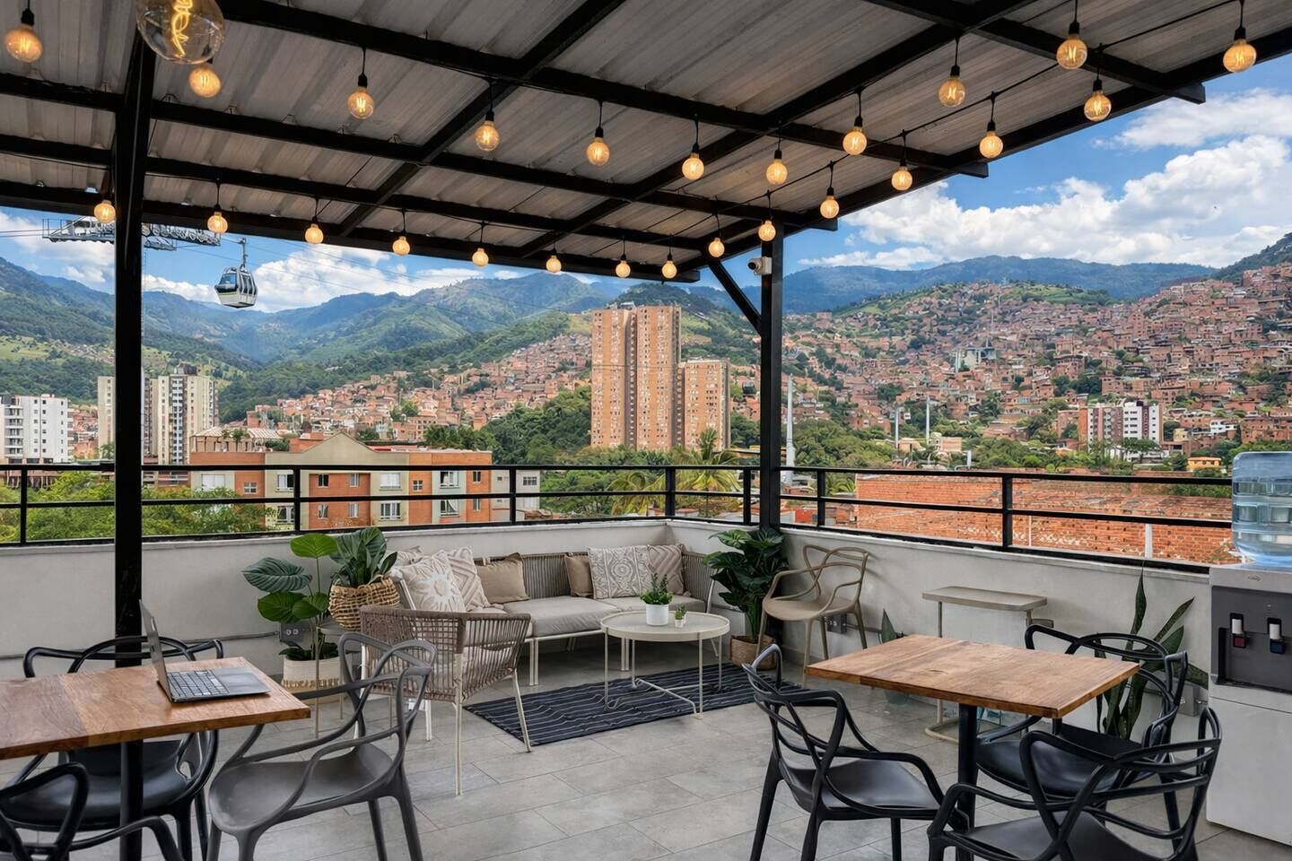 A rooftop terrace with outdoor seating, a view of a cityscape, and mountains in the background.