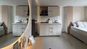 Een moderne keuken met witte kastjes, een magnetron en een fornuis. Er staat een houten eettafel met een ingelijst foto.
