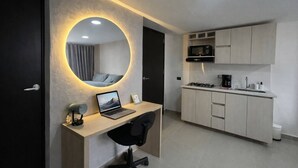 Een moderne slaapkamer met een ronde spiegel, een bureau met een laptop en een bed met uitzicht.