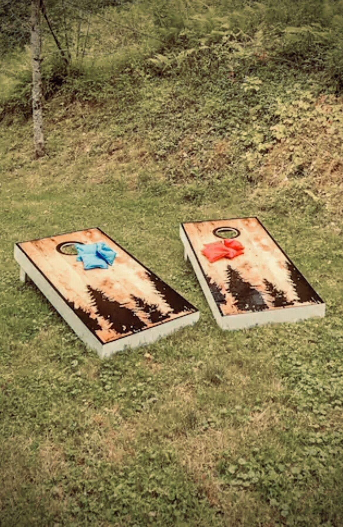 Two wooden planters with a blue and red cloth on a grassy area.