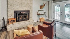 Un salon doté d’une cheminée en pierre, de canapés en cuir et d’une grande fenêtre.