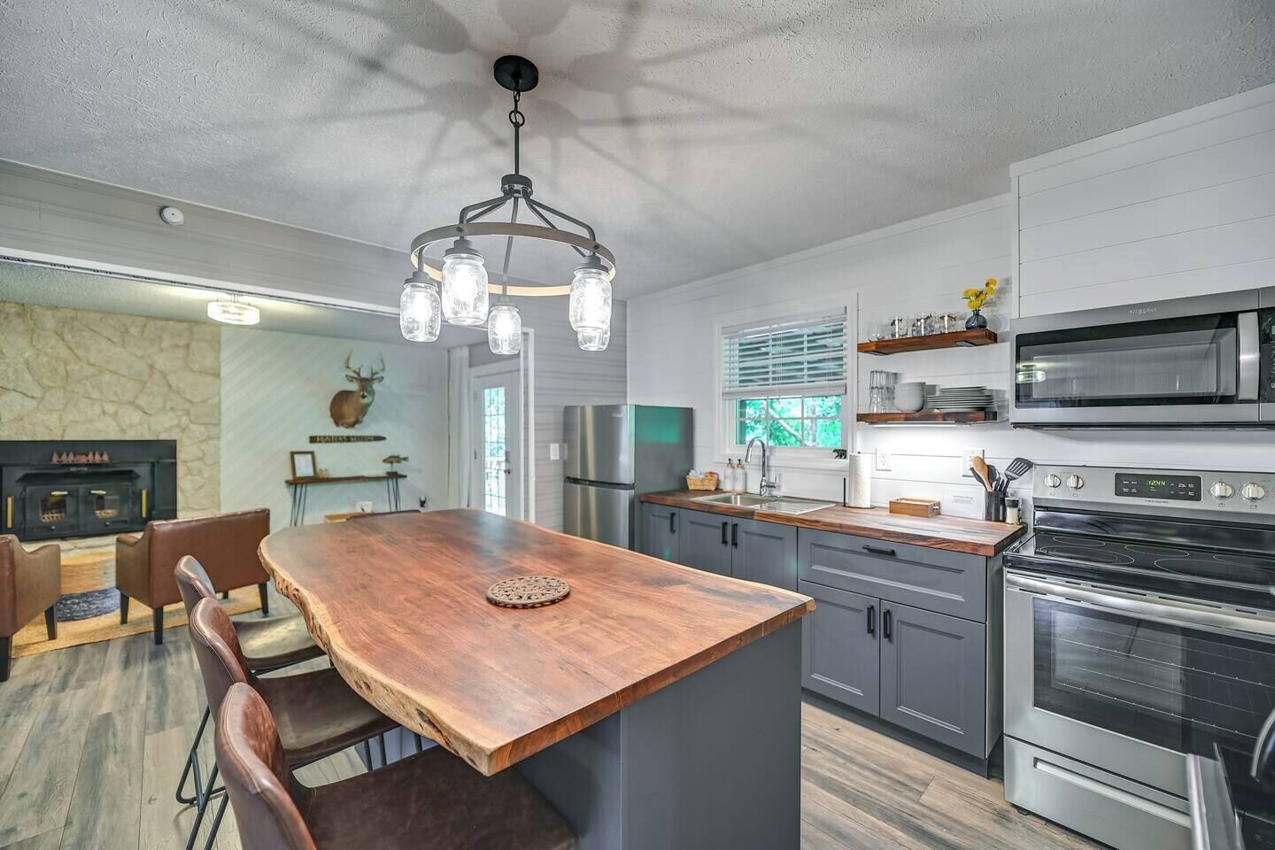 A modern kitchen with a central island, stainless steel appliances, and a stone fireplace.