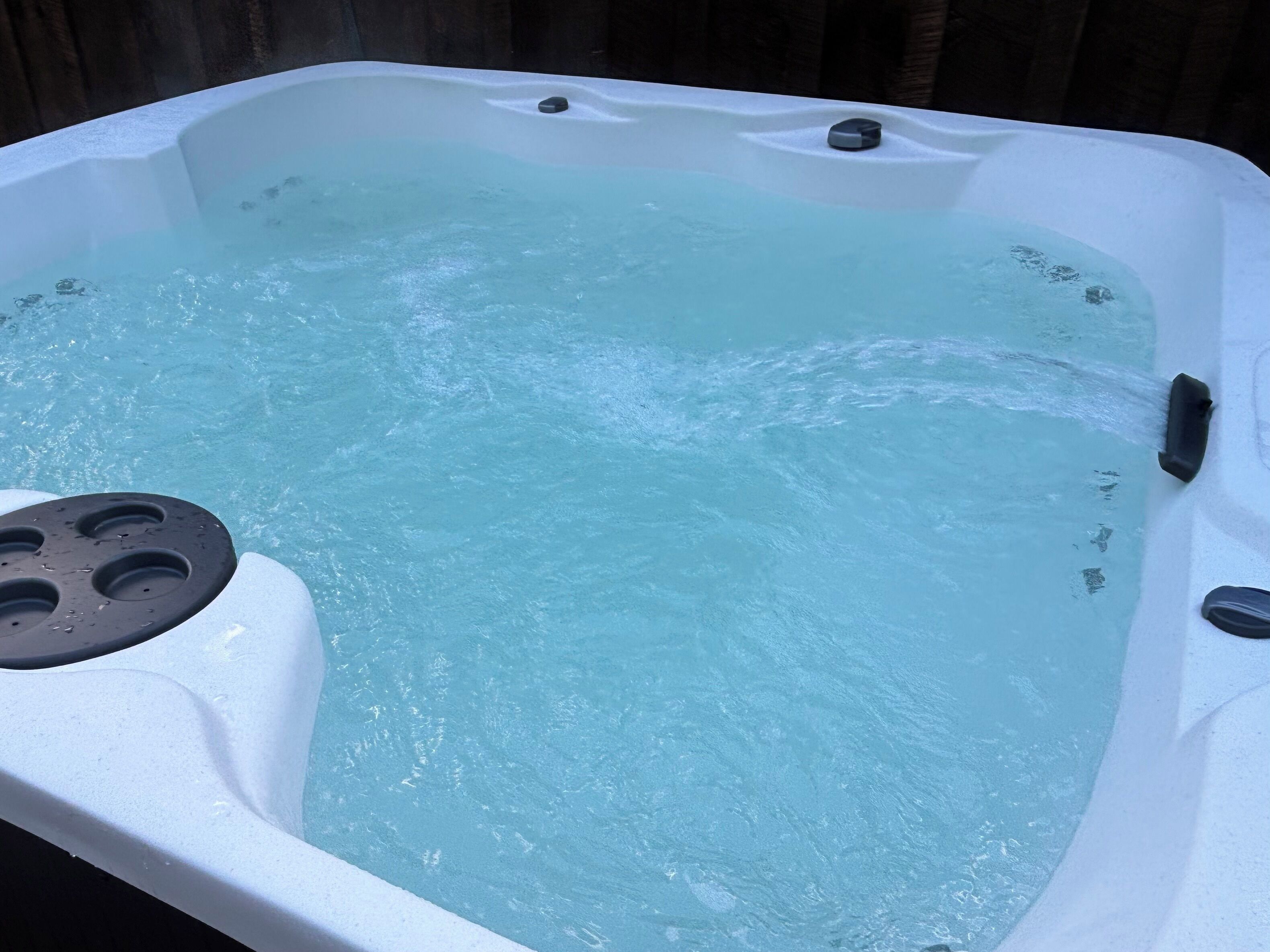 A hot tub with a built-in seat and a control panel.