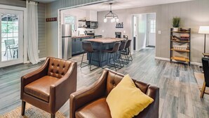 Un vaste espace de vie comprenant une table à manger, des fauteuils en cuir et une cuisine à l’arrière-plan.