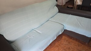 Ett rum med en säng, en stol och ett litet bord.