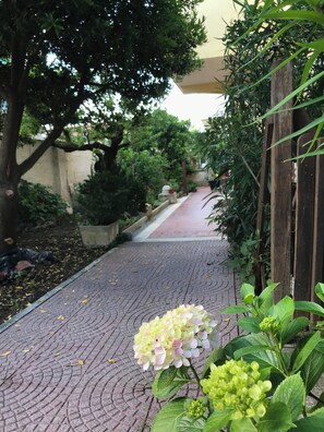 A brick pathway lined with greenery and a wooden fence. - CasaGabbiano- family Beach Stay + Bright Terrace – 50 min to Rome by train (Anzio)