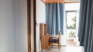Una habitación con techo de madera, un escritorio con silla, una ventana con cortinas y vistas al exterior.
