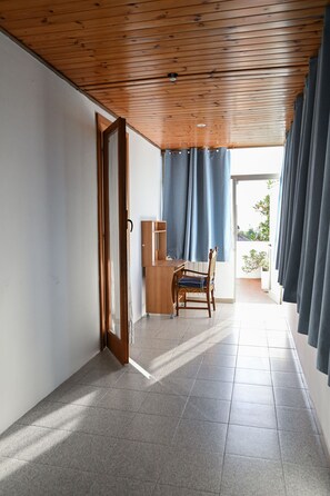A room with a wooden ceiling, a desk with a chair, a window with curtains, and a view of the outside. - CasaGabbiano- family Beach Stay + Bright Terrace – 50 min to Rome by train (Anzio)