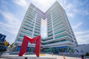 Een modern hoog gebouw met een opvallende rode sculptuur ervoor.
