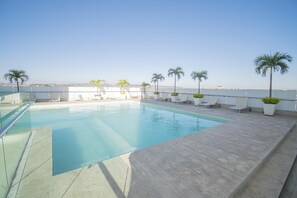A rooftop pool with clear blue water, surrounded by lounge chairs and palm trees. - Malecon Location Torre eMe #1224 with Pool (Mazatlán)